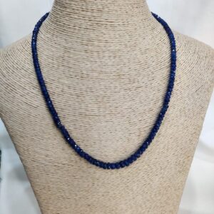 Handcrafted sapphire necklace with faceted blue beads displayed on a neutral woven bust, highlighting Afghan gemstone artistry and emotional symbolism.