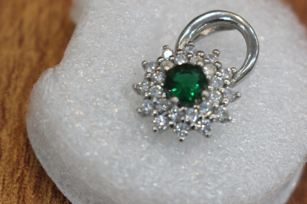 "Green zircon pendant in rhodium-plated silver with white stone floral design, inspired by Afghan heritage and handcrafted for healing and elegance."