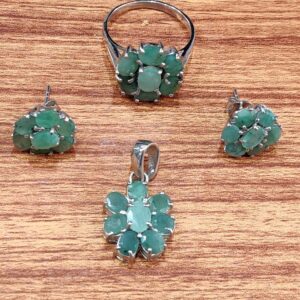 Emerald jewelry set displayed on a wooden surface, featuring a floral design with vibrant green gemstones set in 925 Rhodium Silver. Includes an adjustable ring (sizes 16–19), earrings, and pendant, arranged symmetrically to highlight artisan craftsmanship and cohesive elegance.