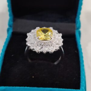 "Zircon special engagement ring in rhodium silver featuring a golden-yellow zircon centerpiece surrounded by diamond-like stones, displayed in a turquoise velvet box."