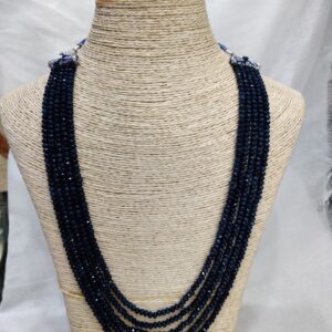 Multi-strand spinal ruby necklace displayed on a beige woven bust. The strands feature rich, deep red spinal ruby beads arranged in elegant layers, radiating warmth and sophistication.