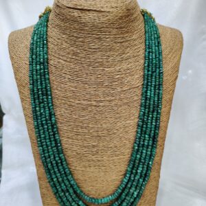 Multi-strand emerald necklace displayed on a woven, textured stand. The necklace features several rows of small, polished emerald beads in rich green tones, arranged in cascading layers that evoke elegance and vitality.