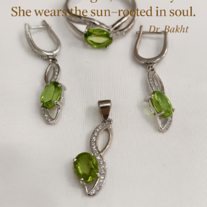 A graceful peridot jewelry set—comprising a silver ring, pendant, and earrings—artfully displayed with soft lighting that highlights the olive-green brilliance of each gemstone. The background is clean and muted, allowing the stones to radiate serenity. Overlaid in elegant font is a poetic quote by Dr. Bakht: “She wears growth, not glitter. She wears light, not luxury. She wears the sun—rooted in soul.” The composition evokes renewal, emotional elegance, and nature’s quiet resilience.