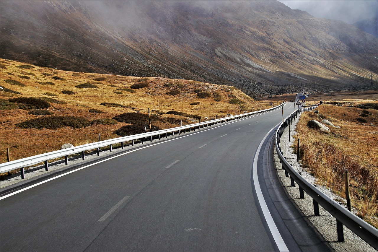 A winding mountain road disappearing into mist, framed by rocky slopes and sparse greenery—symbolizing the quiet journey of silence, emotional boundaries, and sacred restraint.