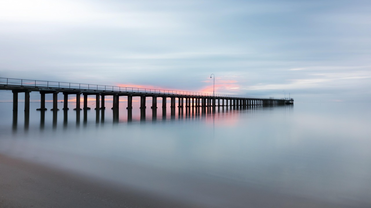 A solitary pier stretching into still waters beneath a muted sky—symbolizing emotional clarity, sacred restraint, and the quiet strength of silence.